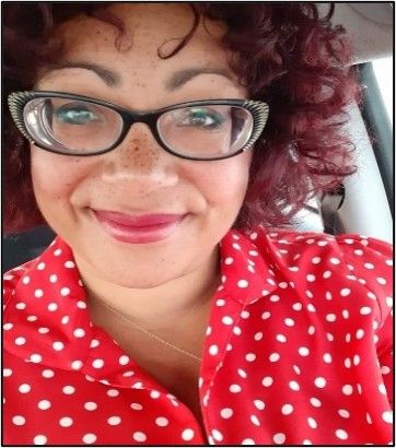 Grinning woman with glasses, curly hair and a red top